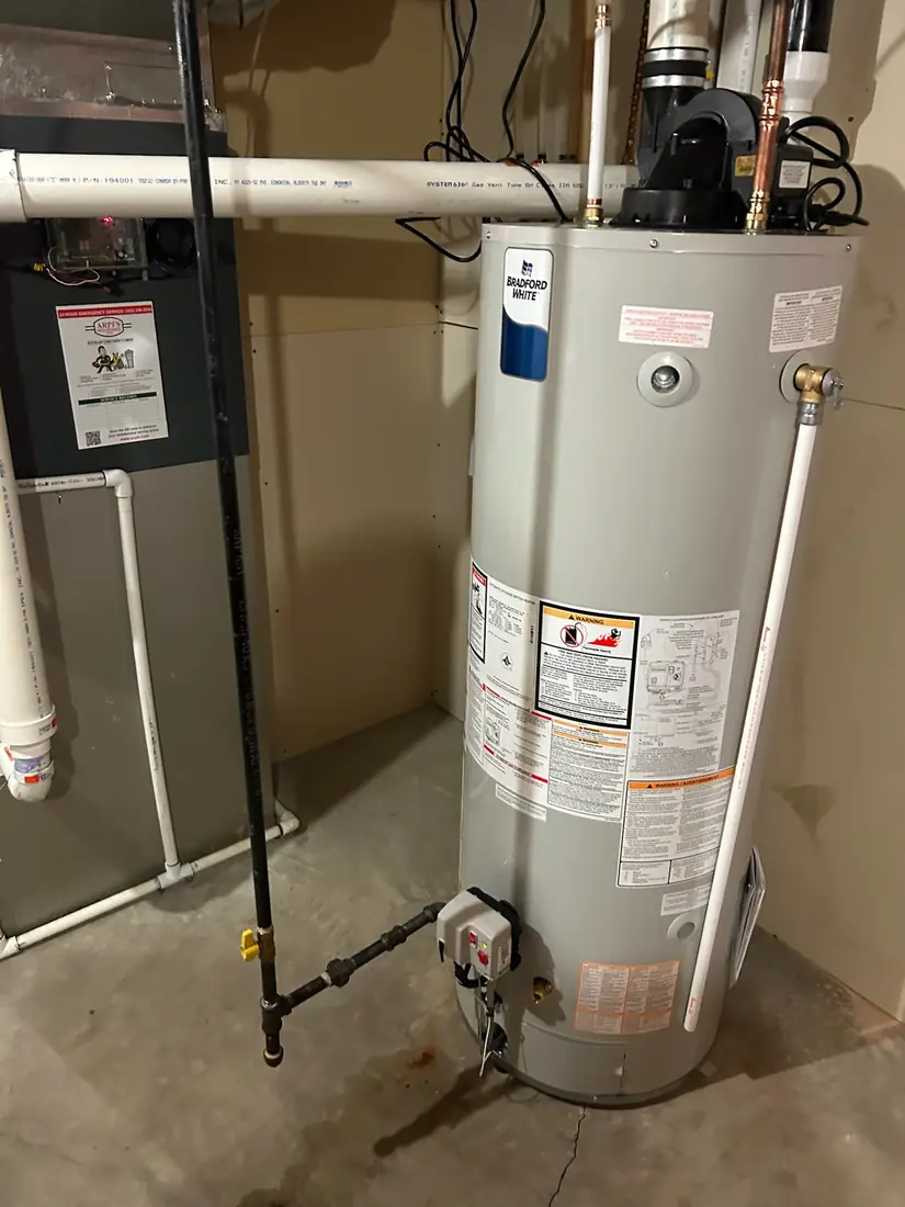 Bradford White gas water heater beside a furnace in a utility room